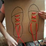 a cardboard box with shoes drawn on it and string attached to the shoelaces