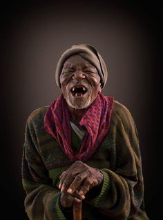 an old man with his mouth open and holding a cane in one hand while wearing a scarf on the other