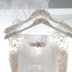 a wedding dress hanging on a hanger in front of a window with the words luxury collection written below it