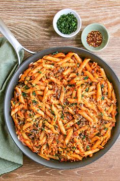 a pan filled with pasta and sauce on top of a wooden table