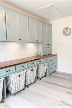 an empty laundry room with grey cabinets and wooden counter tops