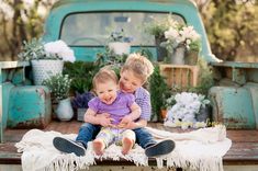 two young children sitting on the back of a truck