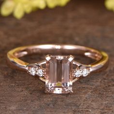 an engagement ring with a pink diamond surrounded by three white diamonds on a wooden surface