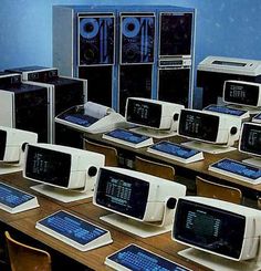 there are many old computers on the desks in front of each other, all with different screens and keyboards