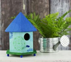 a blue birdhouse sitting on top of a table next to a potted plant