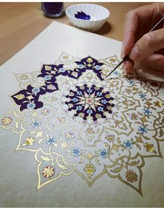 a person is painting an intricate design on a piece of paper