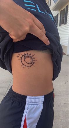 a woman's stomach with a small sun and moon tattoo on her lower back