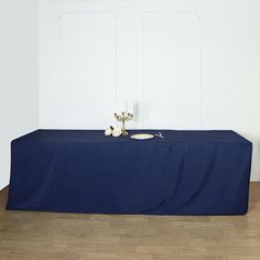 a blue table cloth with two candles on it in front of a white wall and wood floor