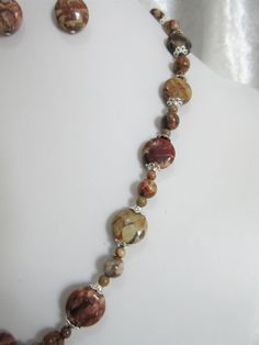 "Birdseye rhyolite jasper is a beautiful, unusual, brown gemstone. Occasional eye-like swirls of brown beige and rust colors run through the stone. The pendant is charming! The necklace is 18\" long with a 3\" silver plated extender. The pendant is a 1.5\" oval. The beads are 4mm rounds, 8mm rounds, and 14mm flat rounds. Silver tone bead caps encase the larger beads. All beads are birdseye rhyolite jasper. The earrings hang 1\" from the loop of the silver plated ear wires. This set will be slipp Earthy Jasper Jewelry With Natural Stones, Brown Jasper Gemstone Necklaces, Unique Brown Jasper Jewelry, Brown Jasper For Jewelry Making, Brown Jasper Gemstone Bead Necklaces, Brown Jasper Gemstone Bead Necklace, Brown Jasper Gemstone Beaded Necklace, Brown Jasper Gemstone Jewelry, Brown Jasper Necklace With Gemstone Beads