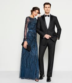 a man in a tuxedo and a woman in a gown pose for the camera