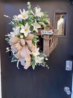 a wreath on the front door with flowers and a welcome sign hanging from it's side