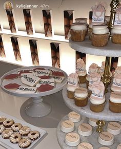 three tiered trays with cupcakes and cookies on them are displayed in front of photos