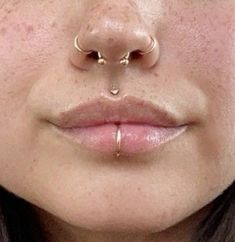 a close up view of a woman's nose with piercings on her nose