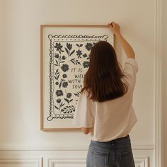 a woman is painting on the wall with black and white flowers