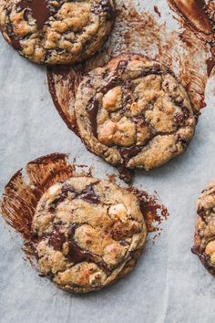 chocolate chip cookies are sitting on a piece of parchment paper and drizzled with melted chocolate