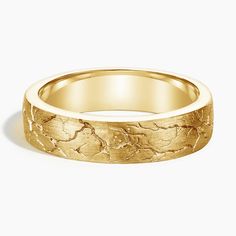 a yellow gold wedding ring with an intricate design on the outside and inside, set against a white background