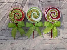 three lollipops with green bows on them sitting in front of a brick wall