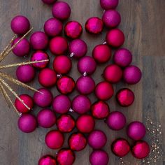 purple and red ornaments on a wooden table with gold trim around the edges, along with sprinkles