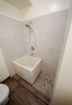 a white bath tub sitting inside of a bathroom next to a toilet and shower head