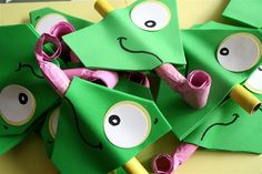 some green paper bags with pink handles and eyes on them are sitting on a table