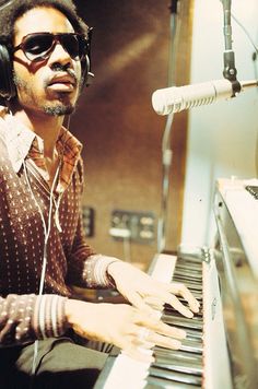 a man wearing headphones sitting at a piano