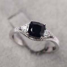 a black and white diamond ring sitting on top of a gray surface with diamonds around it