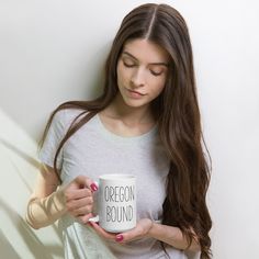 a woman holding a coffee mug with a cross on it