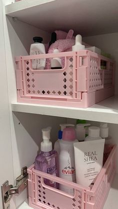 two pink baskets filled with personal care items on top of a white shelf in a bathroom