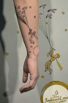 a person with a tattoo on their arm holding onto a balloon that is flying through the air