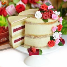 a white cake with red, pink and white flowers on the top is cut in half