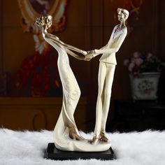 a statue of two people holding hands on top of a white furnishing area