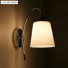 a wall light with a white shade on it's side and the lamp turned off