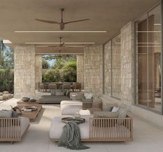 a living room filled with lots of furniture next to a stone covered wall and ceiling fan