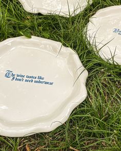 three white plates sitting in the grass on top of each other with words written on them