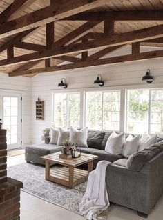 a living room filled with furniture and windows covered in wood planks on the ceiling