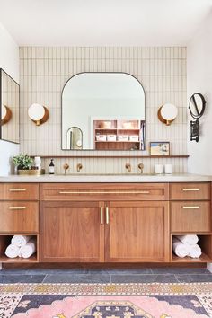 a bathroom with a large mirror above the sink and two wooden cabinets on either side