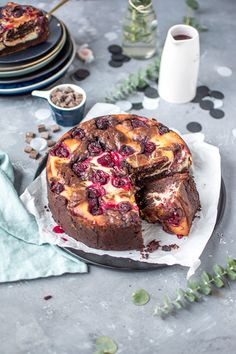 a chocolate cake with cranberries and cream filling on a plate next to other desserts