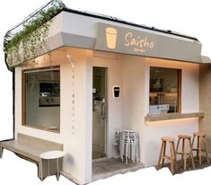 the outside of a small restaurant with stools in front of it and plants growing on the roof