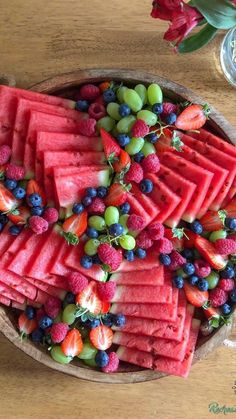 watermelon, grapes and strawberries are arranged in a bowl on a table