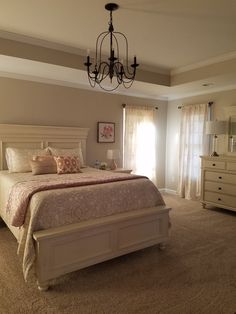 a bedroom with a bed, dresser and chandelier in the middle of it