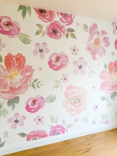 an empty room with flowers painted on the wall and wood flooring in front of it