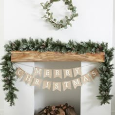 a fireplace mantle decorated for christmas with garland and pine cones