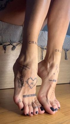 two people with tattoos on their feet sitting on a bed and one person has her foot in the air