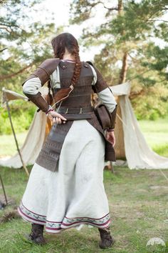 a woman dressed in medieval clothing standing on the grass