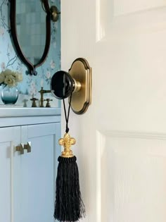 a bathroom door handle with a tassel hanging from it's side next to a sink