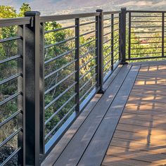 a wooden deck with metal railings and mountains in the background