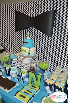 a table topped with cake and cupcakes next to a black and white wall