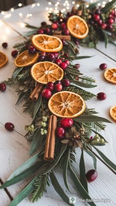 an arrangement of orange slices and cinnamons on a table with greenery, lights and garland