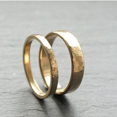 two gold wedding bands sitting on top of each other