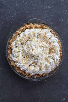 a pie topped with whipped cream on top of a black table next to a fork